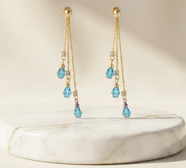 Three-Strand Crystal Bead Drop Earrings in Aqua Blue. Three fine gold strands finished with faceted crystal beads that catch the light as you move.