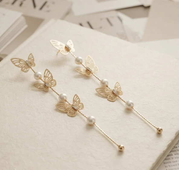 Butterfly Pearl Long Drop Earrings in Gold. Delicate filigree butterflies and pearls cascading on a long fine chain.