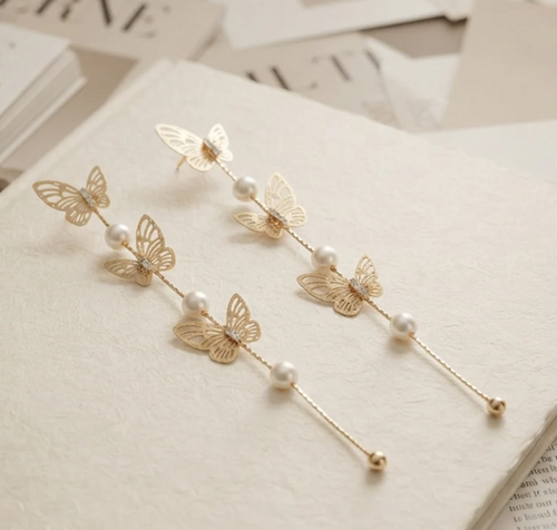 Butterfly Pearl Long Drop Earrings in Gold. Delicate filigree butterflies and pearls cascading on a long fine chain.
