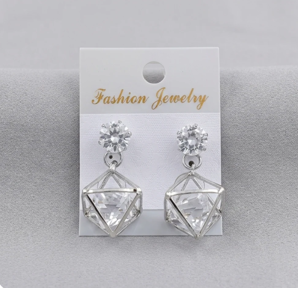 Silver Geometric Crystal Cage Drop Earrings. A faceted crystal held in an open geometric silver cage, hanging from a sparkling solitaire stud.