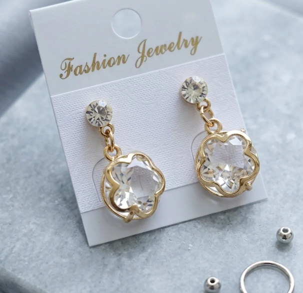 Gold Flower Frame Crystal Drop Earrings. A clear crystal framed by a gold flower outline, on a petite solitaire stud.