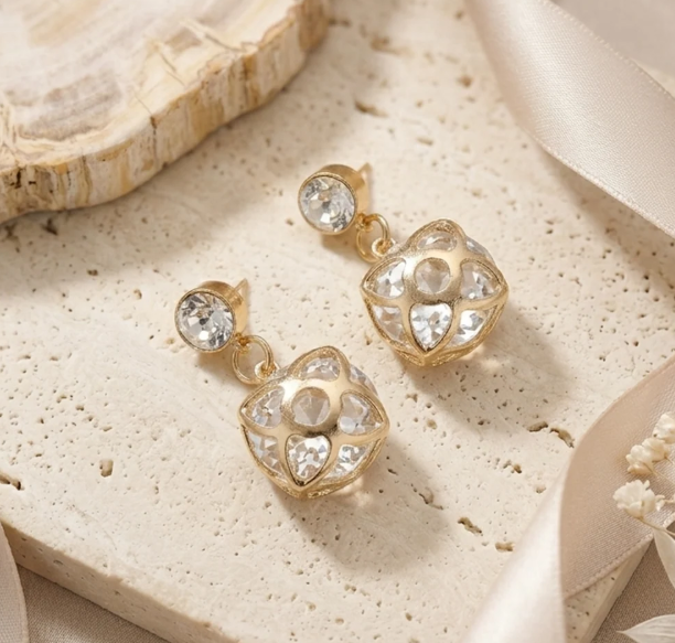 Flower Cage Crystal Drop Earrings in Gold. A rounded flower-shaped cage studded with crystals, on a solitaire stud top.