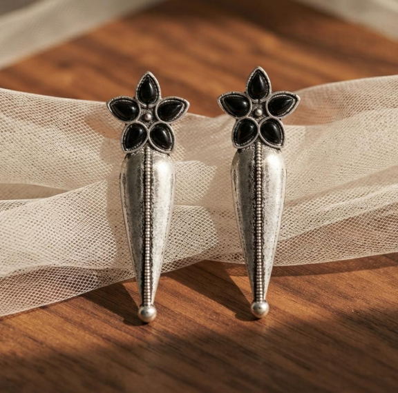 Flower Stud Silver Drop Earrings in Black. Oxidised silver-finish earrings with a five-petal stone flower stud and a long textured teardrop drop with a beaded centre line.
