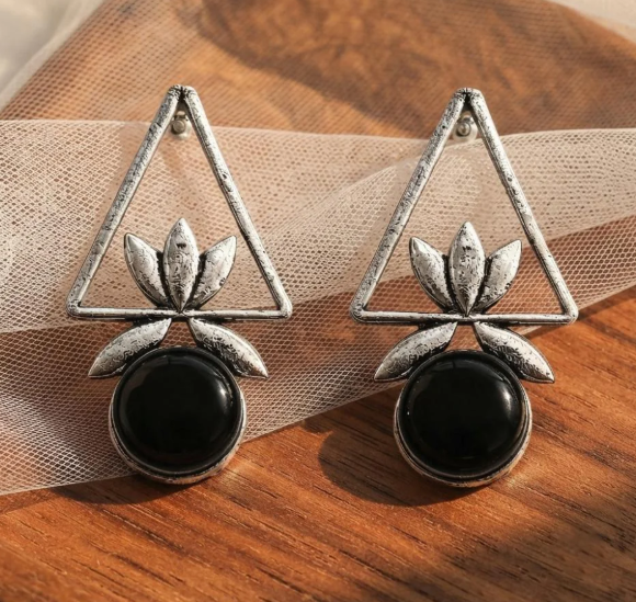 Triangle Lotus Drop Earrings in Black. Oxidised silver-finish earrings with an open triangle frame, sculpted lotus leaves and a round polished stone drop.